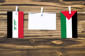 Hanging flags of Iraq and Palestine attached to rope with clothes pins with copy space on white...