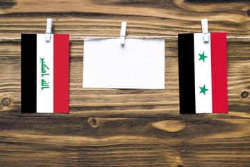 Hanging flags of Iraq and Syria attached to rope with clothes pins with copy space on white note...