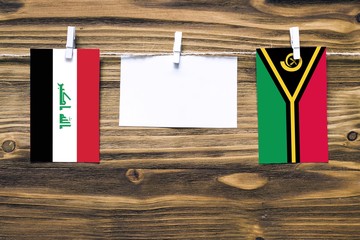 Hanging flags of Iraq and Vanuatu attached to rope with clothes pins with copy space on white note...