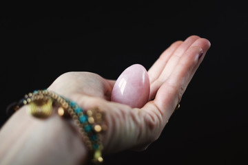 woman holding in hand a vaginal (yoni) egg. Rose quartz crystal jade egg. Copy space