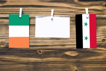 Hanging flags of Ireland and Syria attached to rope with clothes pins with copy space on white note...