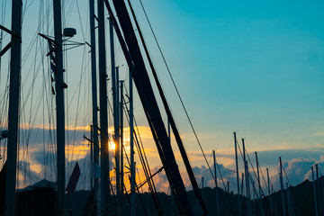 Sun bursts through masts of moored yachts