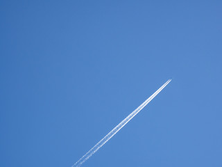 青空に浮かぶ飛行機と飛行機雲の様子