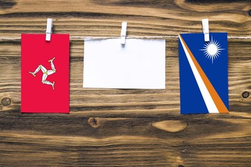 Hanging flags of Isle Of Man and Marshall Islands attached to rope with clothes pins with copy...