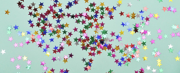 Festive background. Colorful glitter stars on mint color background.