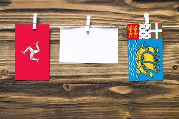 Hanging flags of Isle Of Man and Saint Pierre And Miquelon attached to rope with clothes pins with...