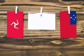 Hanging flags of Isle Of Man and Samoa attached to rope with clothes pins with copy space on white...