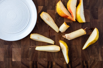 Bartlett pear slices on a wood cutting board, white stoneware plate