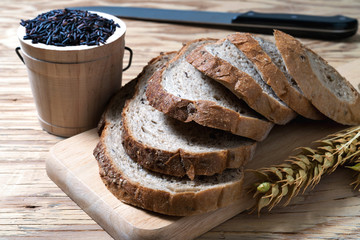 closeup bread loaf and wheat ears and berries rice on wooden background.