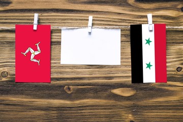 Hanging flags of Isle Of Man and Syria attached to rope with clothes pins with copy space on white...