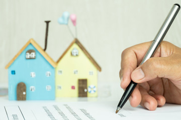 Businessman writing signature in documents agreement contract for family and buy new house or property investment project with minimal home. Investment mortgage agent marketing in real estate concept.