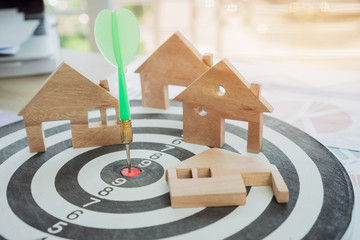 Dart arrow or dartboard hitting on number target center with miniature wooden house models. Success...