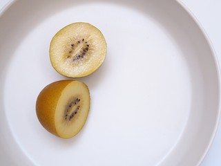 gold kiwi fruit on white plate with copy space.