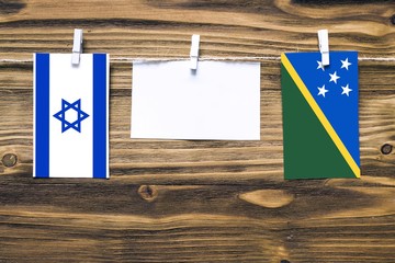 Hanging flags of Israel and Solomon Islands attached to rope with clothes pins with copy space on...