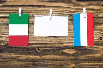 Hanging flags of Italy and Luxembourg attached to rope with clothes pins with copy space on white...