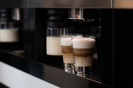 Two cups with cappuccino in a coffee machine