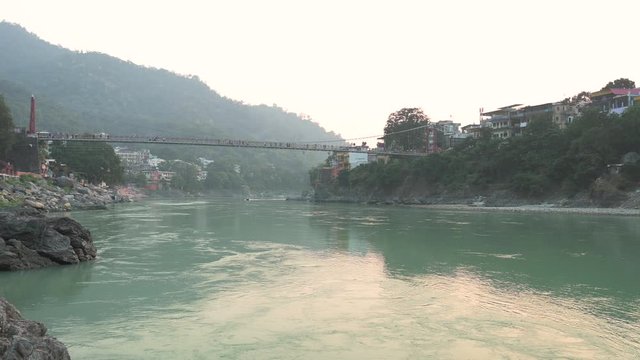 Stunning video of the Ganga river embankment with the Lakshman Jhula bridge and the Tera Manzil Temple (Trimbakeshwar) during a beautiful sunset. Rishikesh, Uttarakhand, India.