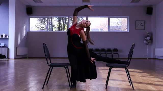Professional female dancer dances around two chairs