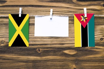 Hanging flags of Jamaica and Mozambique attached to rope with clothes pins with copy space on white...