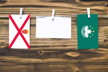 Hanging flags of Jersey and Macao attached to rope with clothes pins with copy space on white note...