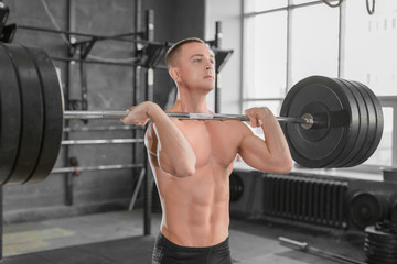 Close up portrait of a sporty man with barbell in gym.