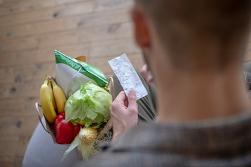 Receipt in hands of man after doing groceries shopping