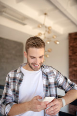 Obraz premium Handsome man smiling while reading message from girlfriend