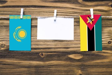 Hanging flags of Kazakhstan and Mozambique attached to rope with clothes pins with copy space on...