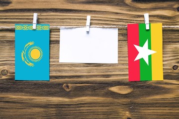 Hanging flags of Kazakhstan and Myanmar attached to rope with clothes pins with copy space on white...