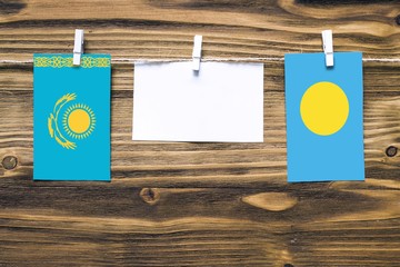 Hanging flags of Kazakhstan and Palau attached to rope with clothes pins with copy space on white...