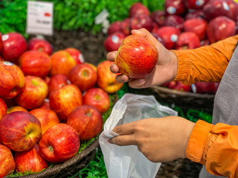 Human Hand Picking An Apple And Using Bio-plastic Bag