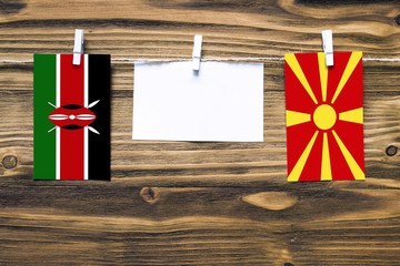 Hanging flags of Kenya and Macedonia attached to rope with clothes pins with copy space on white...