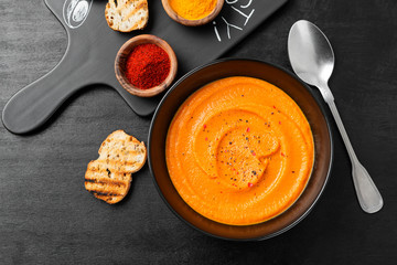Pumpkin and carrot soup with spices on black background. Top view.