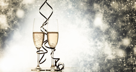 two champagne glasses with ribbons against holiday lights and fireworks - New Year celebrations