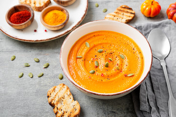 Pumpkin and carrot soup with spices on  on grey stone background. 