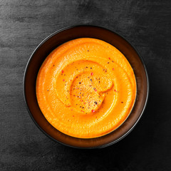 Pumpkin and carrot soup with spices on black background. Top view.