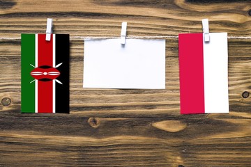 Hanging flags of Kenya and Poland attached to rope with clothes pins with copy space on white note...