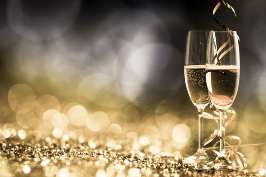 two champagne glasses with ribbons against holiday lights and fireworks - New Year celebrations