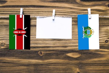 Hanging flags of Kenya and San Marino attached to rope with clothes pins with copy space on white...