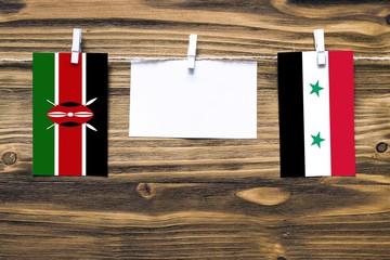 Hanging flags of Kenya and Syria attached to rope with clothes pins with copy space on white note...