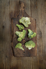 Obraz na płótnie Canvas Organic fresh raw broccoli isolated on a wooden rustic board. Healthy food concept. Vegan. Top view. Flat lay. With copy space for text. Vertical photo. Green food background, poster, pattern.