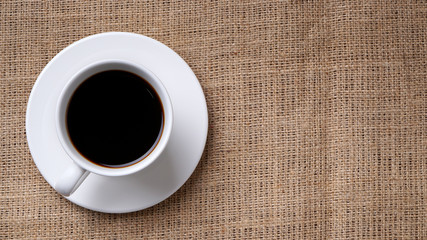 Obraz na płótnie Canvas cup of coffee and coffee beans on jute
