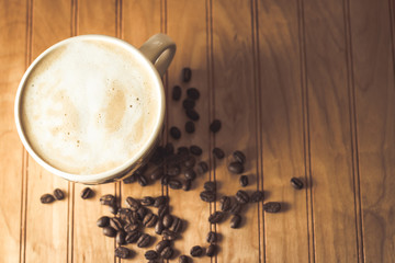 Overhead Angle of a Cup of coffee and coffee beans on a Wooden Table