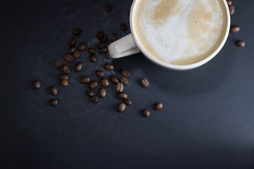 Overhead Angle of Cup of coffee and coffee beans on a Black Table