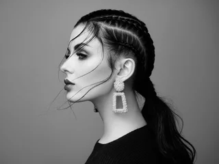 Brünettes Mädchen mit perfektem Make-up. Schöne vorbildliche Frau mit lockiger Frisur. Pflege- und Schönheitsprodukte für das Haar. Dame mit geflochtenem Haar. Modell mit Schmuck. Schwarz-Weiß-Foto © Oleg Gekman