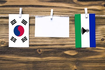 Hanging flags of South Korea and Lesotho attached to rope with clothes pins with copy space on...