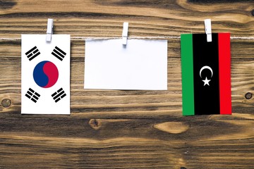 Hanging flags of South Korea and Libya attached to rope with clothes pins with copy space on white...