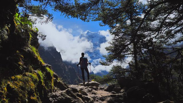 Woman hiking in in the forest valley of the Himalayan mountains, overlooking on the mount Thamserku summit, handled shot