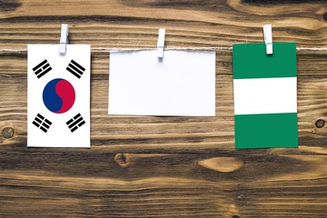 Hanging flags of South Korea and Nigeria attached to rope with clothes pins with copy space on...