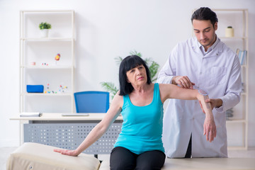 Young male doctor examining old female patient